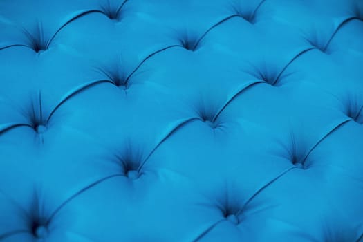 Blue upholstered furniture from fabric texture. Ement quilted sofa. Interior design, headboards made of furniture fabric upholstery. Classic checkered pattern background for furniture, wall, headboard