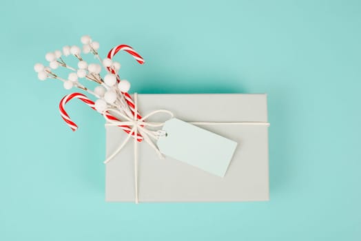 Gift box with a blank tag, snow covered berries and candy cane, christmas holiday wintertime