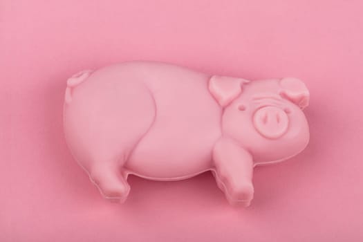 Piece of soap in shape of a Pig from above over pink background.