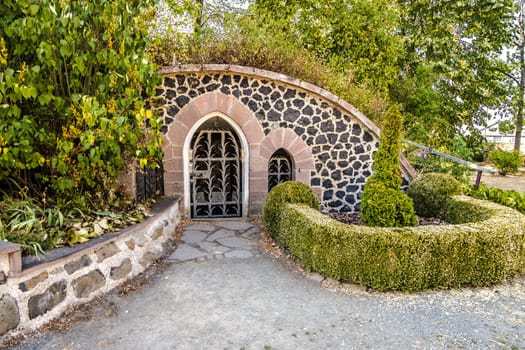 Oval archway with wrought iron gate in the park of Amoeneburg Castle.