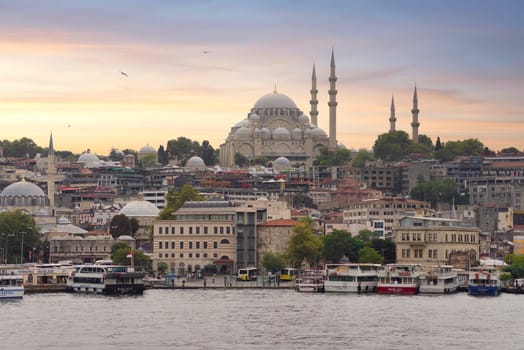 Istanbul, Turkey - August 25, 2022: Istanbul city view from Galata Bridge at Eminonu overlooking the Golden Horn with ferries, ferry terminals, and Suleymaniye Mosque before sunset