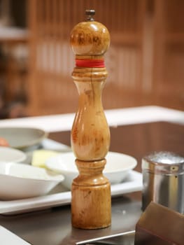 A salt or pepper mill is ready next to the stove in the kitchen.
