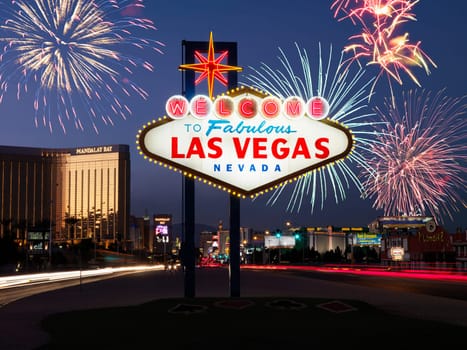 Lighted sign reading Welcome to Fabulous Las Vegas Nevada with fireworks in background. Horizontally framed shot.