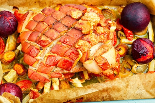 Juicy pork shoulder with skin and bacon cooked with vegetables and plums.