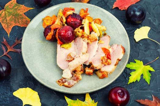 Juicy pork shoulder with skin and bacon cooked with vegetables and plums.