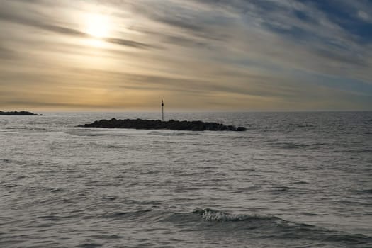 Stone groynes, breakwaters in the water off the coast in Denmark. In the evening with clouds in the sky. Landscape photo by the sea