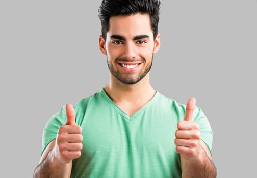 Portrait of handsome young man drinking coffee, isolated on gray background