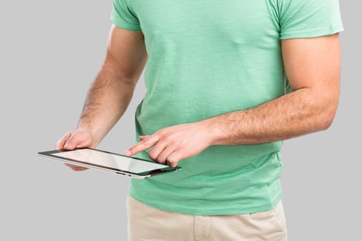 Handsome young man working with a tablet, isolated over gray background