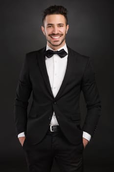 Portrait of a beautiful latin man with tuxedo and holding a clapboard