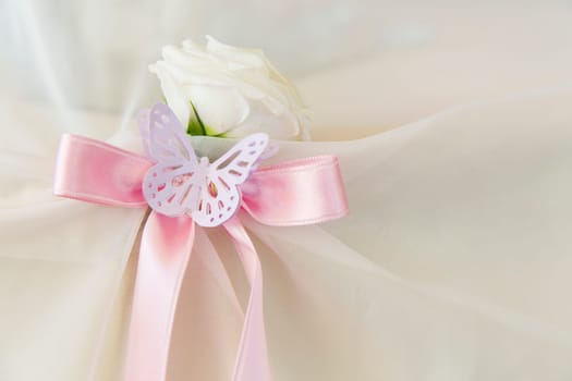 White rose with pink ribbon and paper butterfly