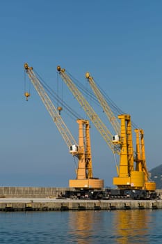 View of three cranes in a commerciial harbor