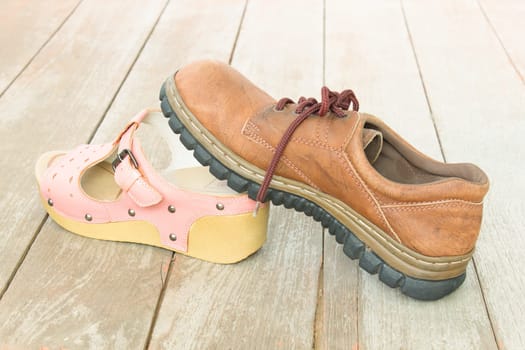 Love or sex or relationship concept background. Man's shoe is making love with Woman's shoe on wood floor.