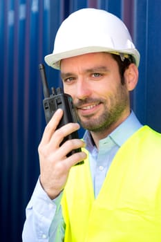 View of a Young Attractive engineer using talkie walkie on the dock