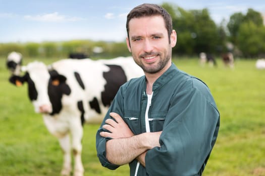 View of a young attractive farmer in a pasture with cows