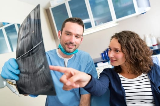 View of a Young attractive dentist showing x-ray to patient