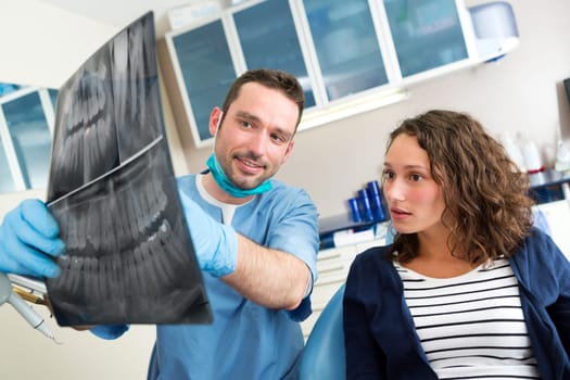 View of a Young attractive dentist showing x-ray to patient