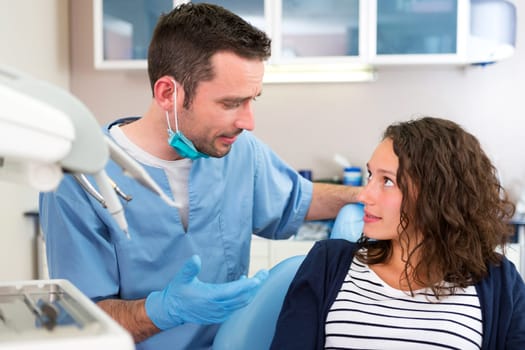 View of a Young attractive dentist explaning his work to a patient