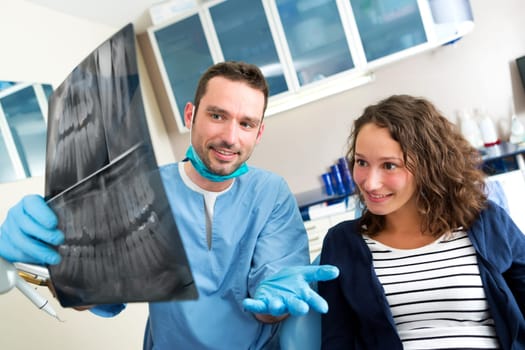 View of a Young attractive dentist showing x-ray to patient