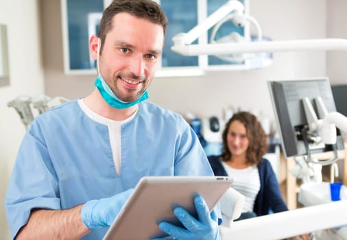View of a young attractive dentist in his office