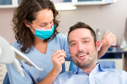 View of a Young attractive man being cured by a dentist