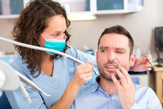 View of a Young attractive man scared to being cured by a dentist