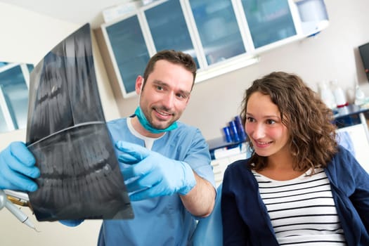 View of a Young attractive dentist showing x-ray to patient