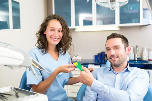 View of a Young attractive dentist taking health insurance card of patient