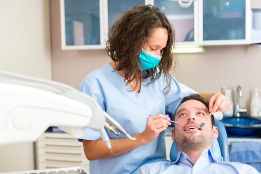 View of a Young attractive man being cured by a dentist
