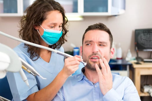 View of a Young attractive man scared to being cured by a dentist