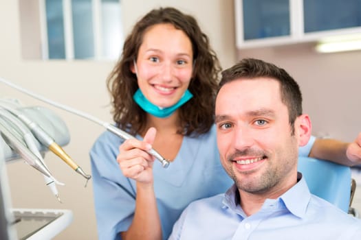 VIew of a Portrait of a young attractive dentist in his office with patient