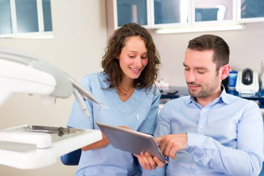 View of a Young attractive dentist explaning his work to a patient