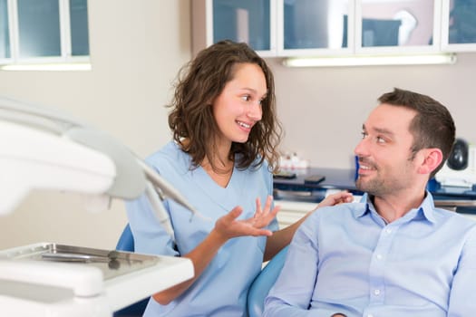 View of a Young attractive dentist explaning his work to a patient