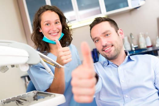 VIew of a Portrait of a young attractive dentist in his office with patient