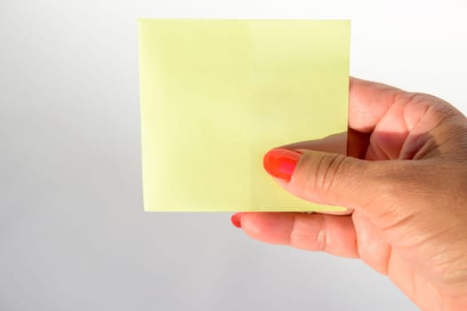 Woman's hand with painted nails holding blank letter paper on pure white background.