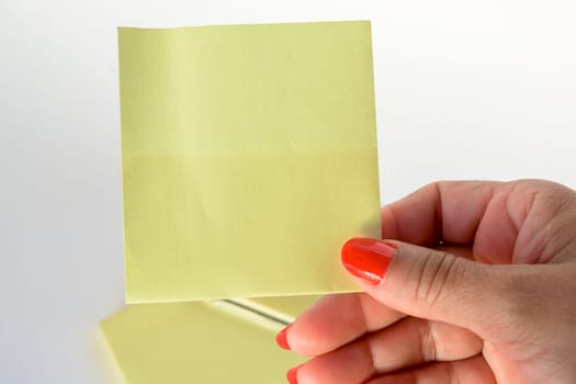 Woman's hand with painted nails holding blank letter paper on pure white background.