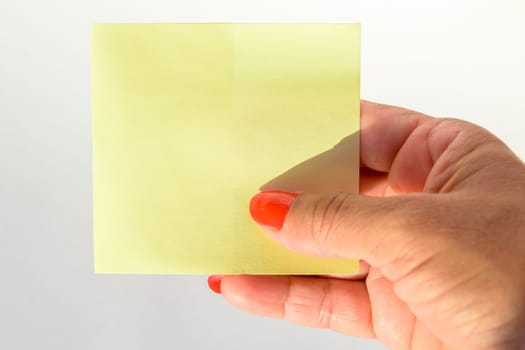Woman's hand with painted nails holding blank letter paper on pure white background.