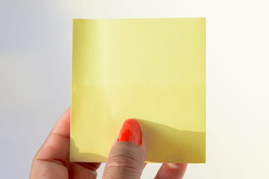 Woman's hand with painted nails holding blank letter paper on pure white background.