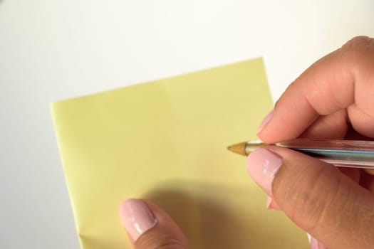 Woman's hand with painted nails holding blank letter paper on pure white background.