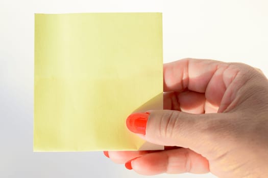 Woman's hand with painted nails holding blank letter paper on pure white background.