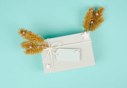 Present box with a blank tag, golden fir branches, christmas holiday wintertime