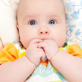 Cute little baby girl holding her hands in mouth