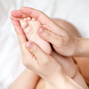 Masseur massaging little baby's foot, shallow focus
