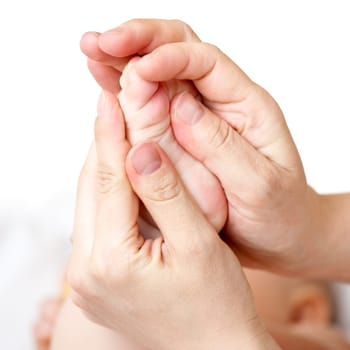Masseur massaging little baby's foot, shallow focus