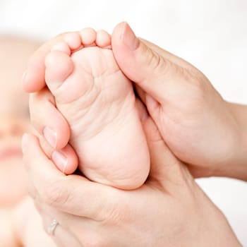 Masseur massaging little baby's foot, shallow focus