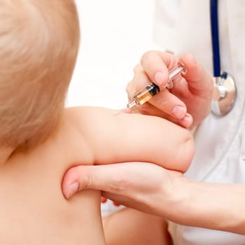 Doctor giving a child an intramuscular injection in arm, shallow DOF