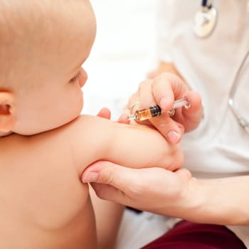 Doctor giving a child an intramuscular injection in arm, shallow DOF