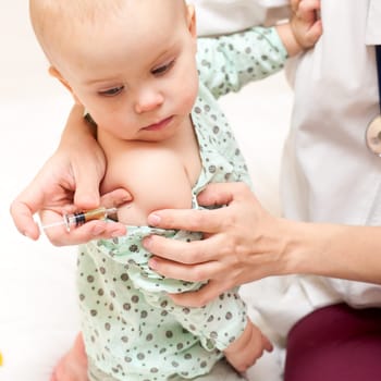 Doctor giving a child an intramuscular injection in arm, shallow DOF