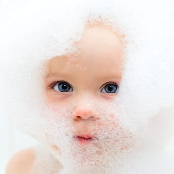 Little baby girl bathing in soapsuds