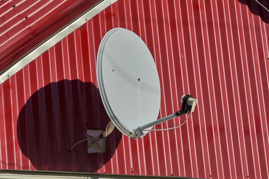 A satellite dish is hanging on the wall of the house. High quality photo