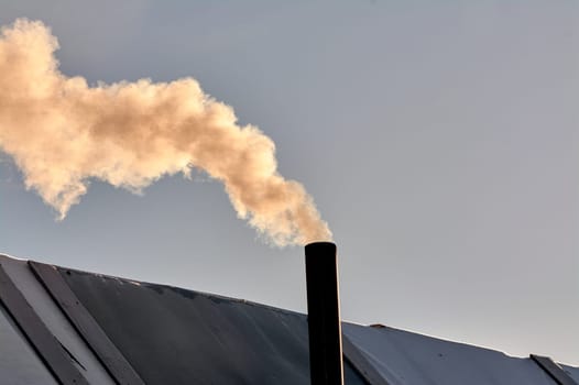 smoke is coming from the chimney of the bourgeoisie. the stove is being heated. High quality photo